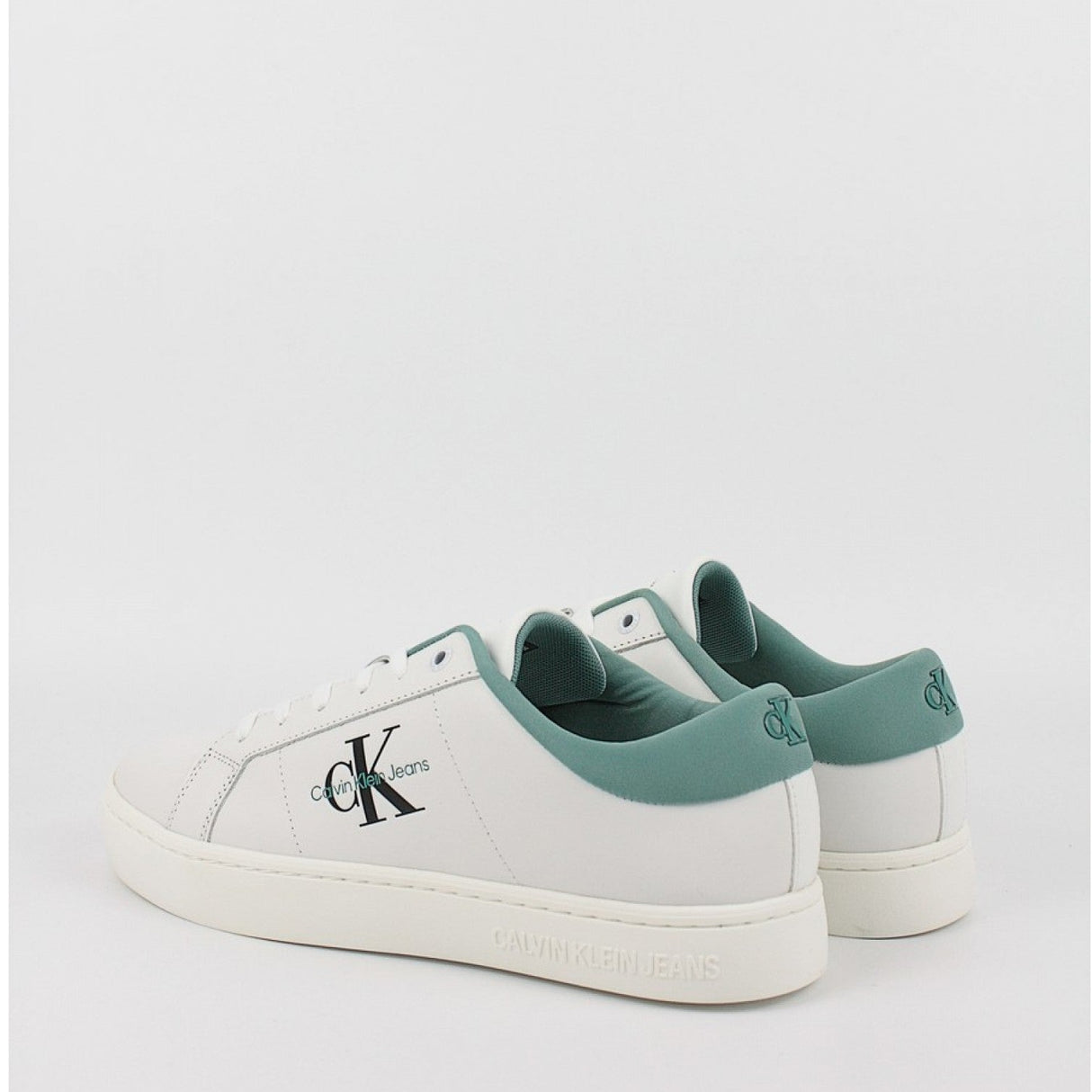 This is a pair of men's Calvin Klein Jeans Classic Cupsole Low Laceup sneakers in bright white leather with a turquoise/oil blue heel tab.