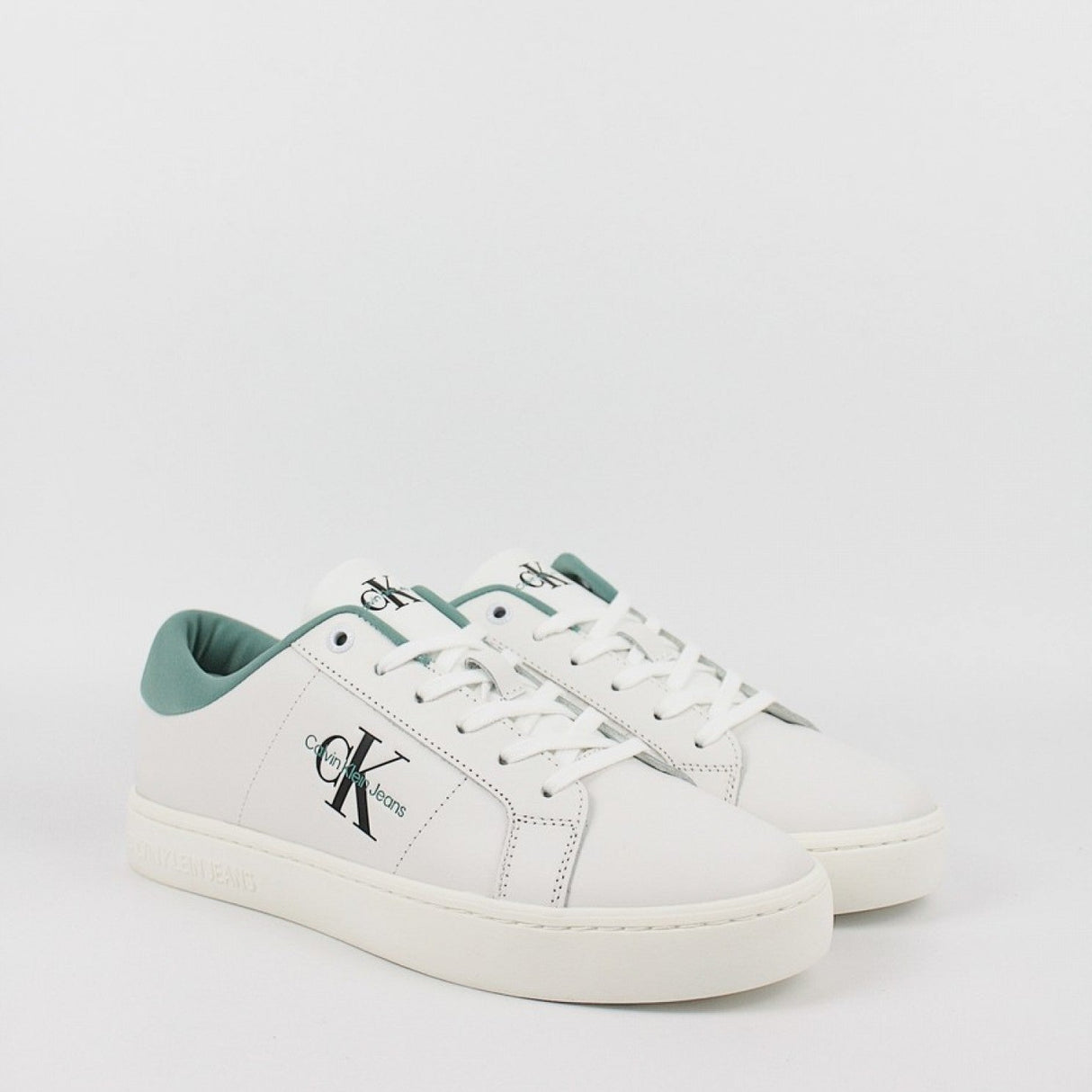 This is a pair of men's Calvin Klein Jeans Classic Cupsole Low Laceup sneakers in bright white leather with a turquoise/oil blue heel tab.